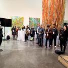 A speaker addresses an audience in a bright, modern space with colorful artwork and a large installation.
